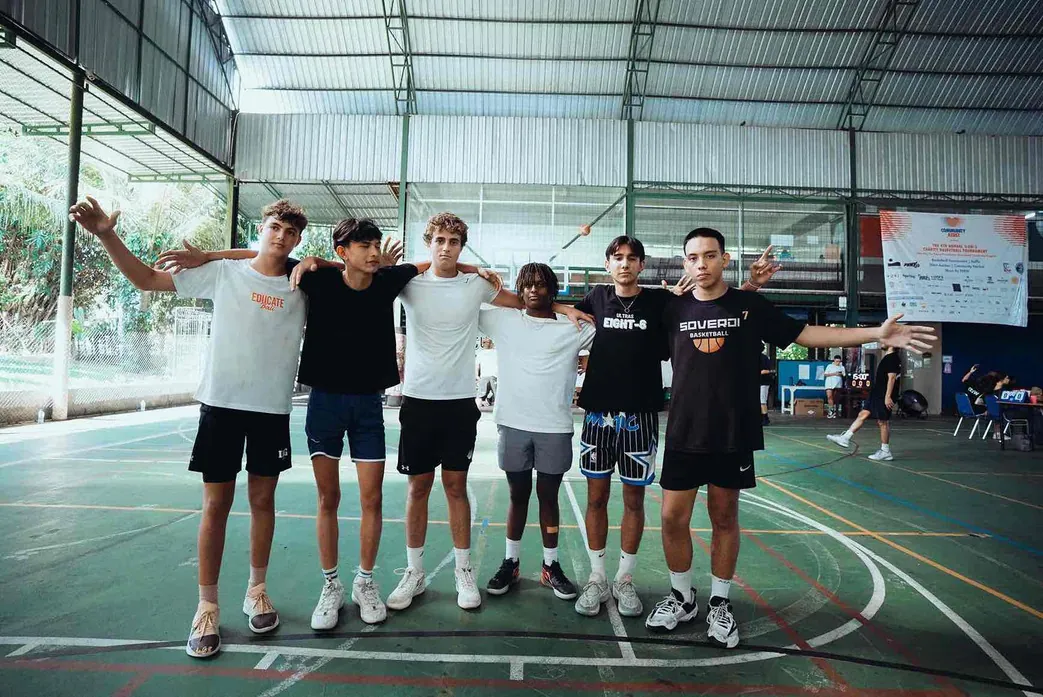 A team of young players, arms around each other, on the court before a game